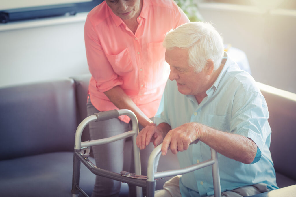 woman helping elder man with walker