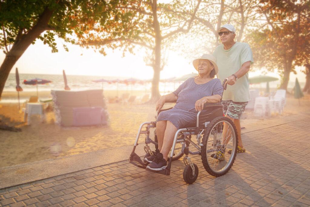 elder man pushing woman in wheelchair